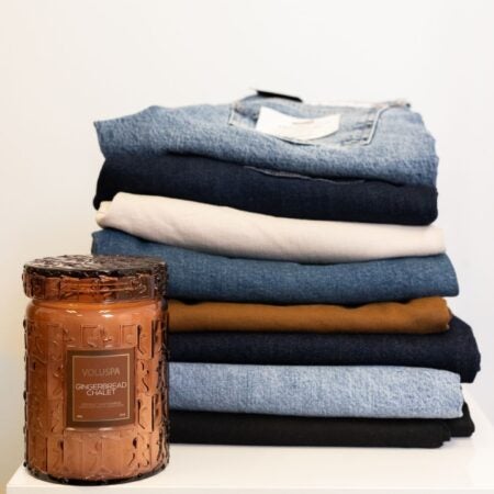 A stack of folded pants with a gingerbread candle in front