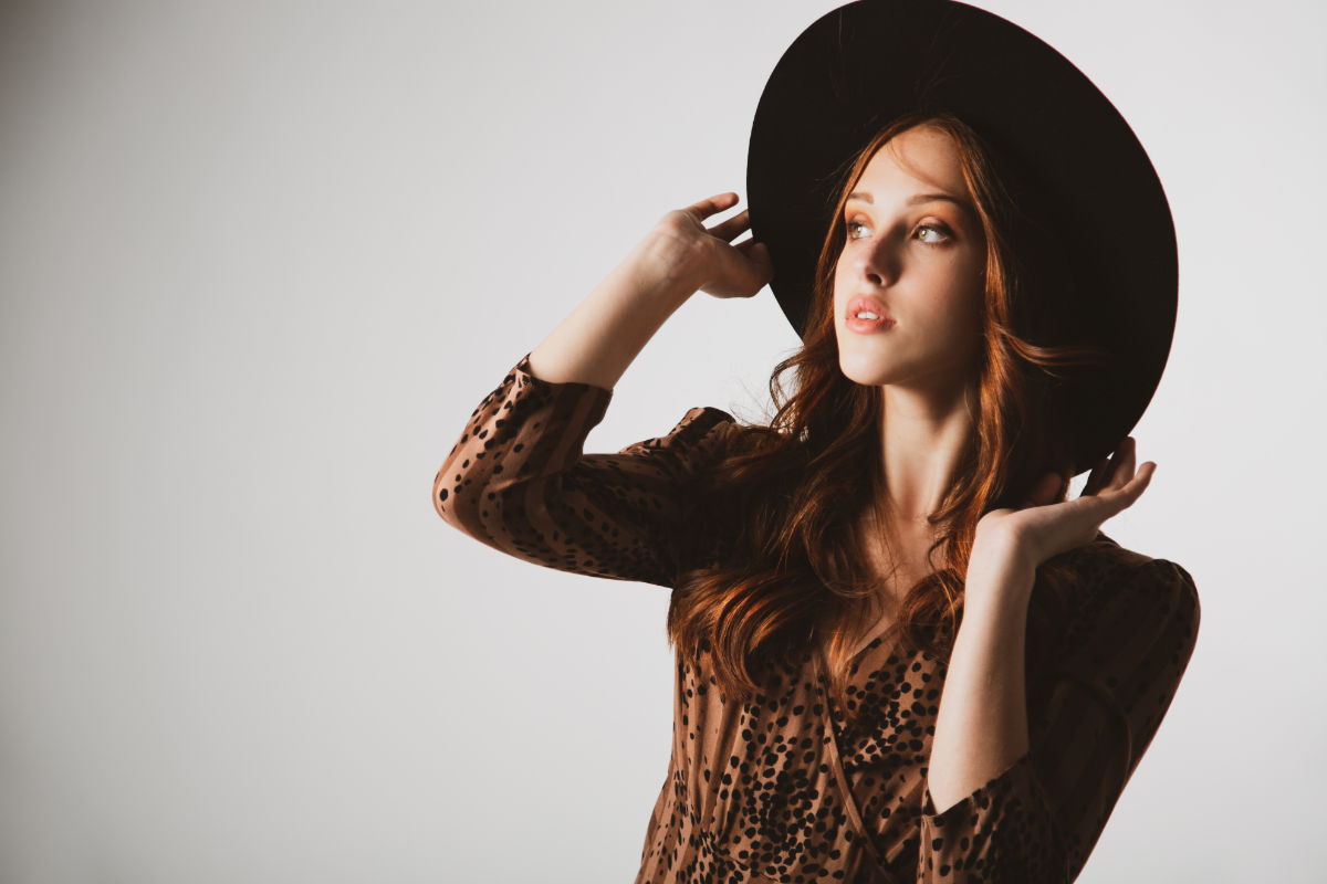a model wearing a rust coloured long sleeve dress and a black hat showcasingStyle Trend Clothiers Warm Weather Accessories