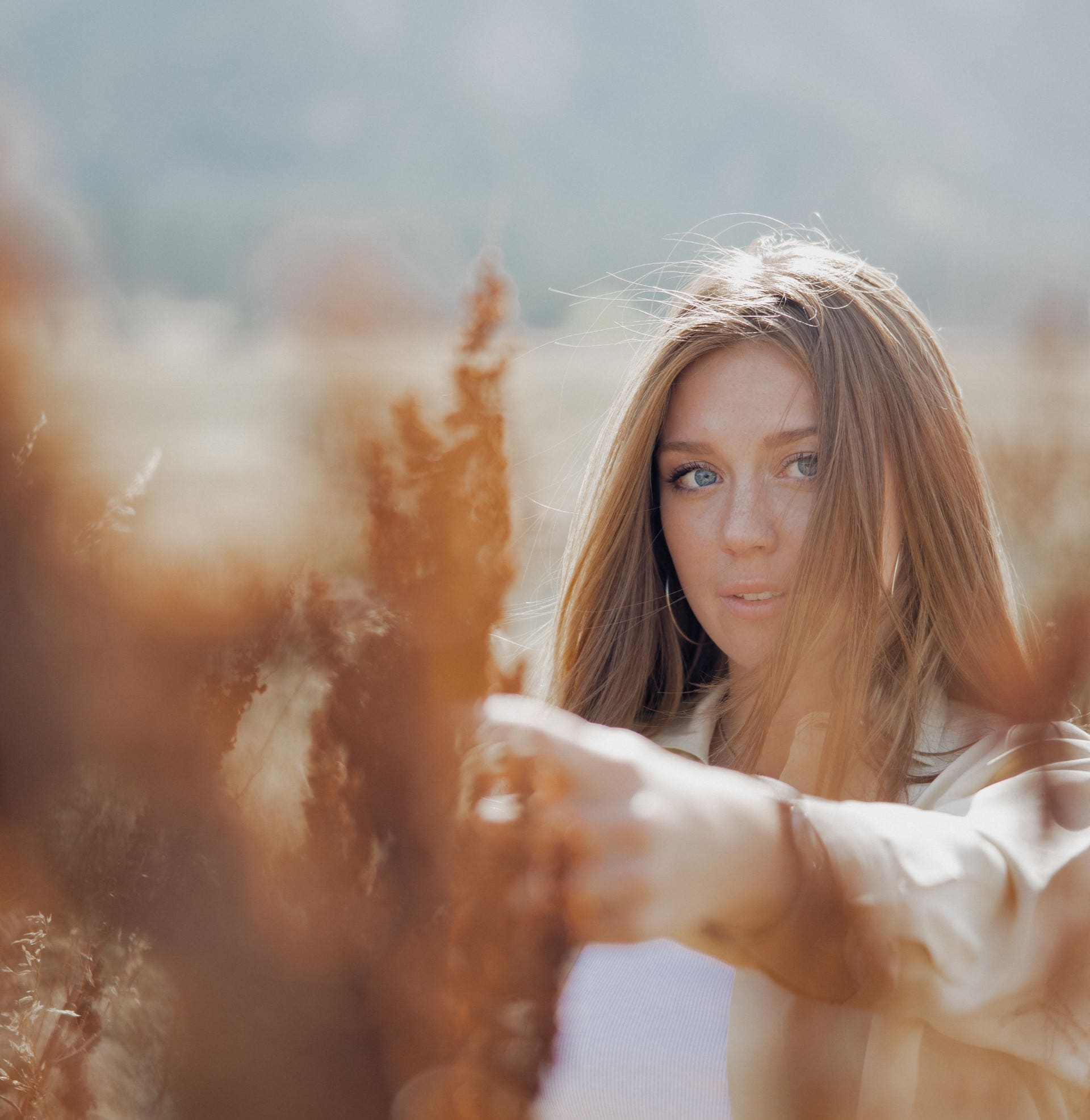 A woman wearing a beige Style Trend Clothiers jacket in a field, for the Careers Banner